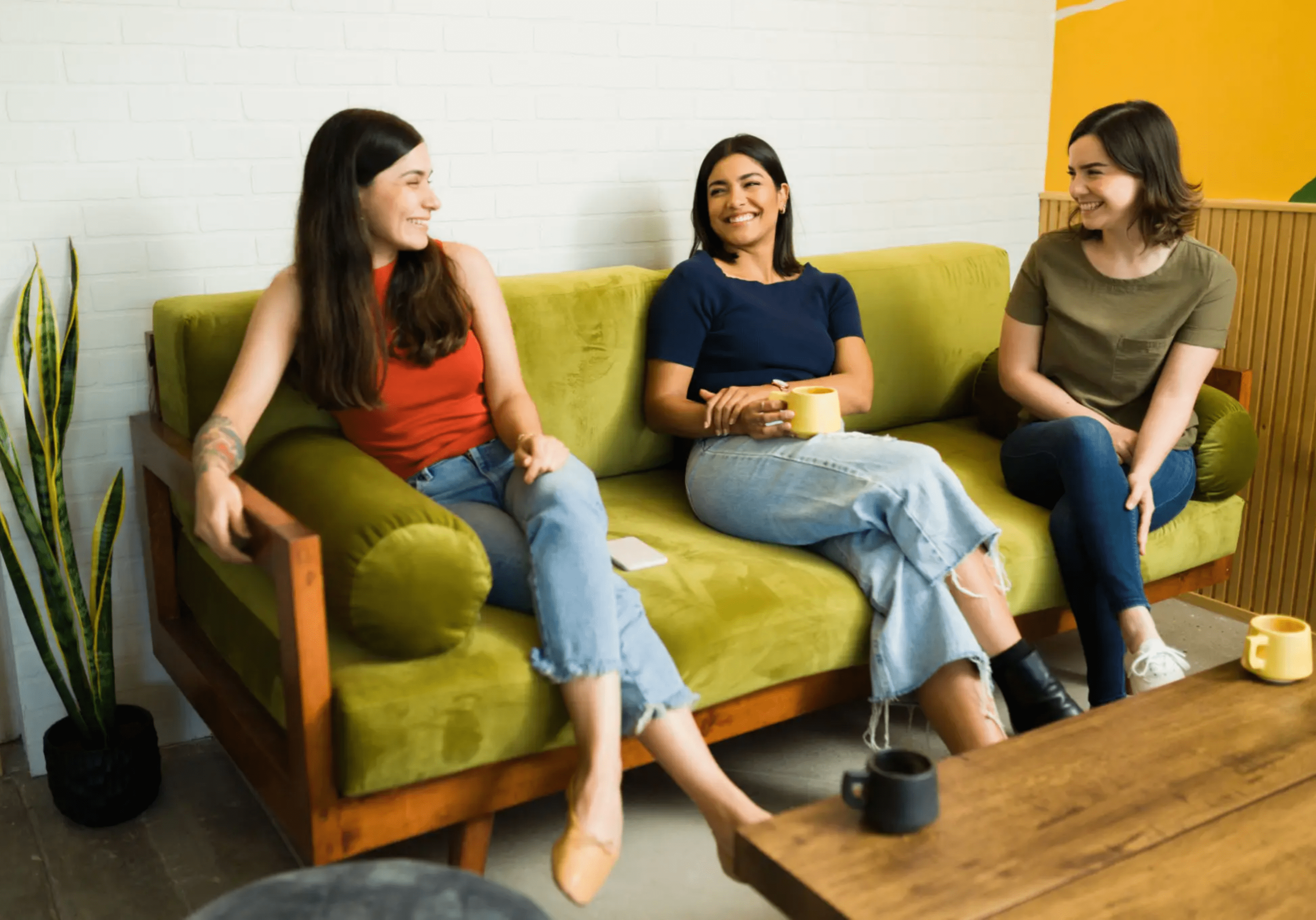 blob-d923448 Three people sitting on a green couch in a room.
